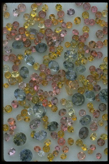 Close-up photograph of a handful of small Montana sapphires of various colors